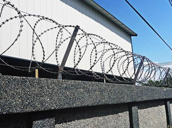 Concertina wire spiral fencing with Y arm support along the perimeter wall